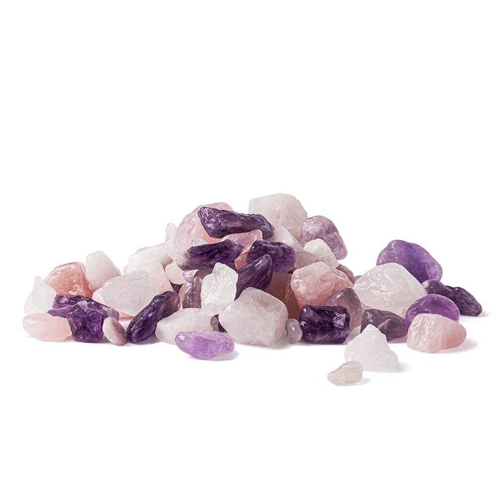Ein Haufen naturbelassener Wassersteine in den Farben Rosa, Violett und Weiß, bestehend aus Rosenquarz, Amethyst und Bergkristall, auf weißem Hintergrund.