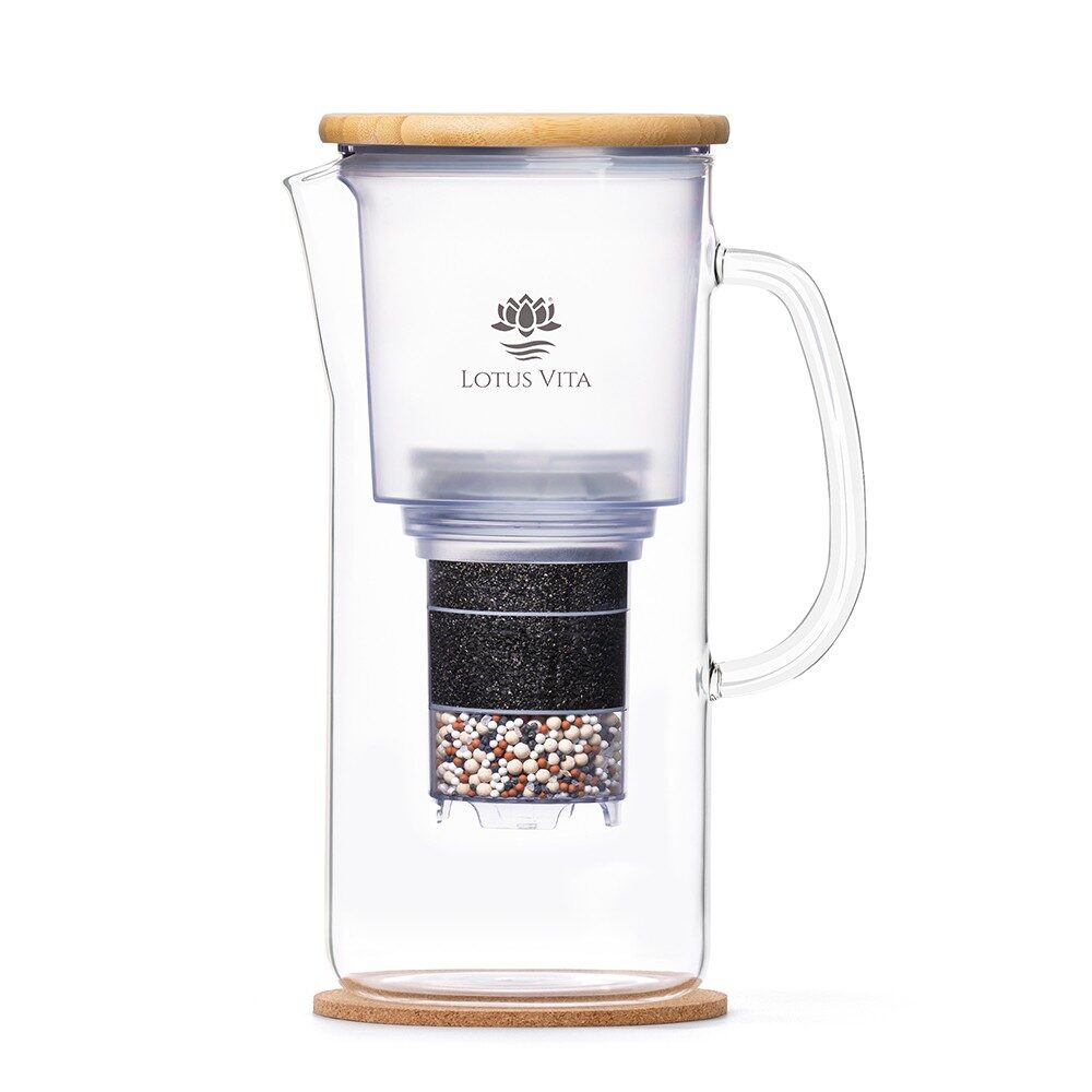 Eine elegante Glas-Filterkaraffe von Lotus Vita mit Bambusdeckel und Kork-Untersetzer, deren mehrstufiger Wasserfilter im Inneren sichtbar ist.